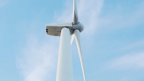Slide large rotating blades of a wind turbine against the blue sky Stock Footage 100653784