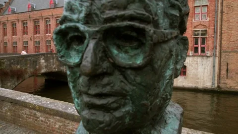 Slide past bust of Frank Van Acker beside the Dijver Canal in Bruges Stock Footage 90454251