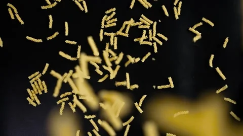 A slide of pasta falling from above on a black background, in slow motion. Stock Footage 276836661