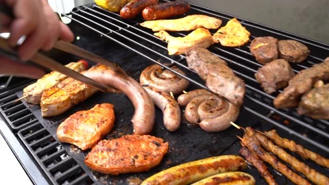 Slide right close up shot of man turing bratwurst sausages on BBQ grill in Stock Footage 136735525