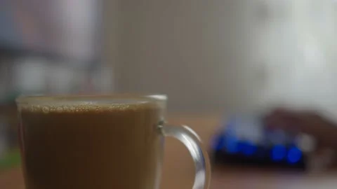Slide shot of a cup of coffee on a worktable and a man coming to work background Stockbeeldmateriaal 234121689