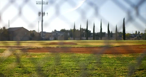 Slide up shot looking at an empty green baseball field diamond from behind Stock Footage 97495753