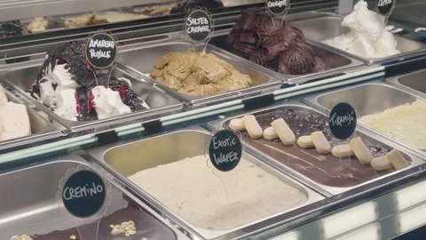 Slide shot of multiple metal boxes with ice cream flavours displayed under glass Stock Footage 304316955