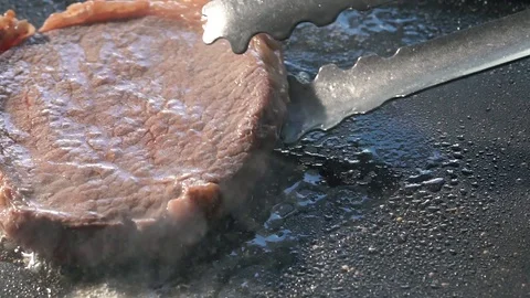 Slide slow motion shot of flip rib eye steak on grill pan Stock Footage 115777840