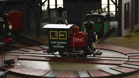 Slider parallax shot of model train engine revealing roundhouse with box car Stock Footage 148605535