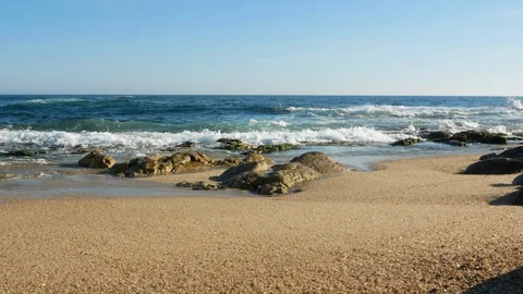 Slider shot along sandy beach on sunny day in summer with rocks on shore Stock Footage 108516919