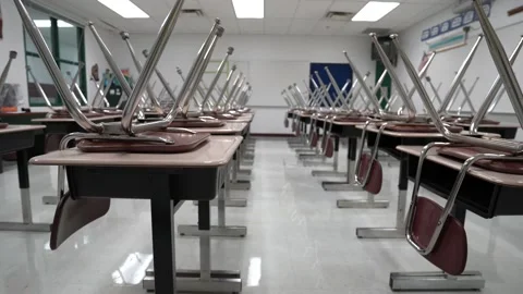 Slider shot to the right of empty school classroom with chairs on the desks. Stock Footage 137641722
