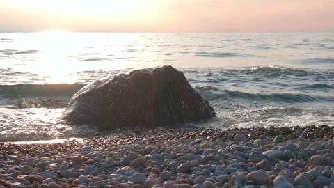 Slider Shot of Small Waves Breaking Over Colorful Boulder Along Beach at Sunset Stock Footage 186594958