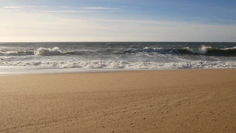 Slider shot, waves breaking on the sandy beach on sunny day with blue sky Stock Footage 103289414