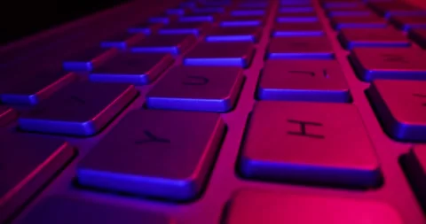 Sliding above laptop computer keyboard in neon lights. cyberspace, gaming c.. Видео 332658388
