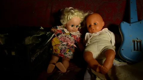Sliding beam of light illuminates the dolls sitting next to each other Stock Footage 120246933
