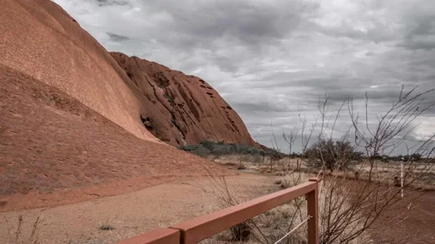 Sliding cinematic timelapse of base of Uluru/Ayers rock in storm clouds. Stock Footage 130761323