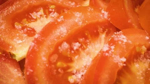 Sliding close-up shot of sliced tomatoes being seasoned with salt. Stock Footage 313833151