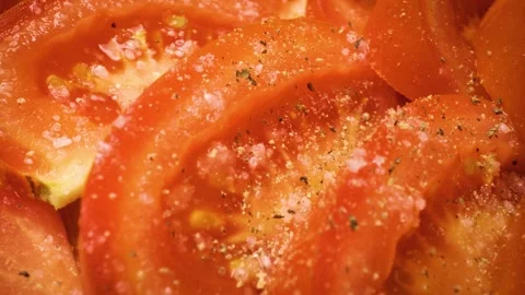 Sliding close-up shot of sliced tomatoes being seasoned with salt and pepper. 스톡 동영상 313833162