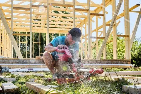 Sliding compound miter saw cutting wooden boards as carpenter works on lumb.. Stock Photos