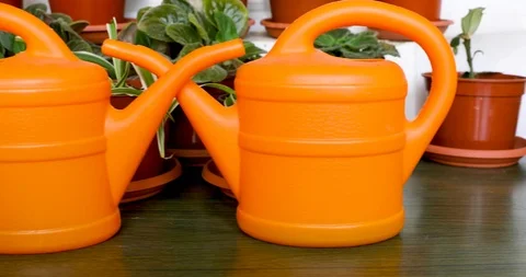 Sliding from right to left along two orange garden watering cans Stock Footage 114450906