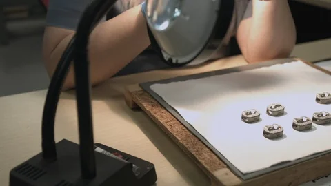 Sliding shot of factory worker inspecting small finished metal parts Stock Footage 116176911