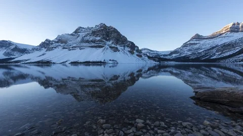 Sliding time lapse of sunlight hitting snowy mountain at a lake Stock Footage 85299395