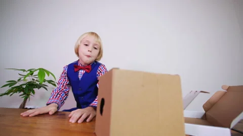 Sliding view of a caucasian boy dressed like a postman opening parcels 스톡 동영상 229619630