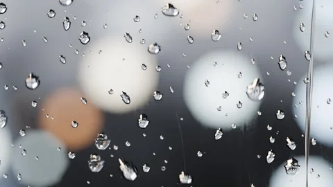 Sliding water droplets elongating merging under gravity down vertical glass pane Stock Footage 341889680
