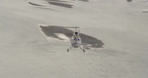 Slight overhead on blue and white helicopter soaring over Alaskan River towards 스톡 동영상 107933532