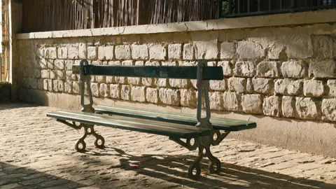 A slightly angled close shot of a classic empty green park bench standing on a c Stock Footage 337414465