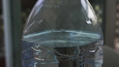 Slightly damaged bottle containing water with green cap. zoom out Stock Footage 143346586