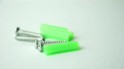 Slightly defocused and closeup of silver metal screw and green plastic anchors.  Video stock 41841358