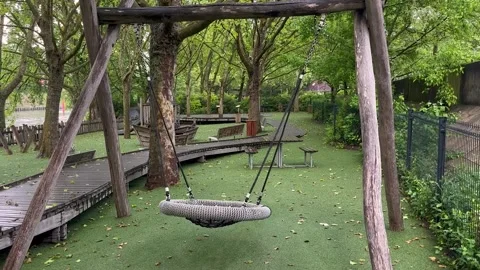 Slightly moving empty swing in the park playground for kids, rest and relax Stock Footage 245117344