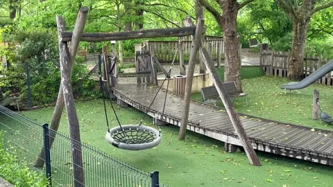 Slightly moving empty swing in the park playground for kids, rest and relax Vidéo 332806330