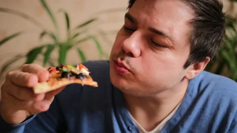 A slightly shaved young man eats a vegetarian pizza Stock Footage 149315394