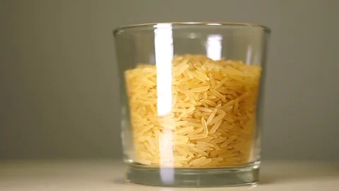 Slim and lengthy raw long grain rice in transparent glass with white reflection 스톡 동영상 75241579