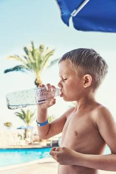 Slim boy with bare torso drinking bottled mineral water 写真素材