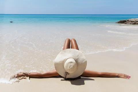 Slim brunette woman in hat sunslasses sunbathe on the beach Stock Photos