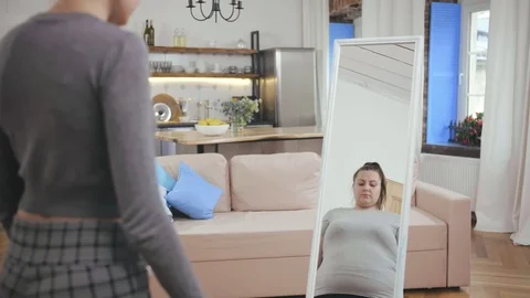 Slim girl looking at fat reflection in mirror. Eating disorder concept, body Vidéo 124657067