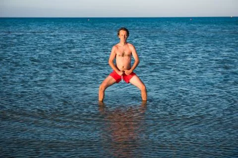 Slim guy posing in red swimwear in sea water Stock Photos