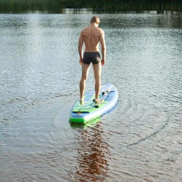 Slim guy on the sup Board. the view from the back, Stock Photos