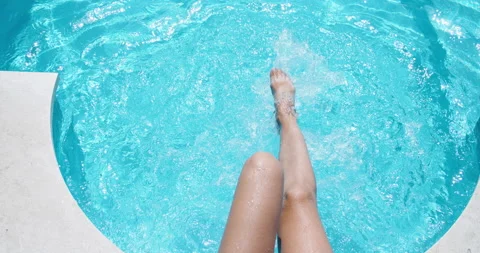 Slim legs close-up in clear blue water in the pool. A woman quickly moves her Stock Footage 139718522