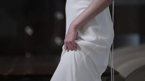 Slim model poses holding long white wedding dress train Stock Footage 130190738