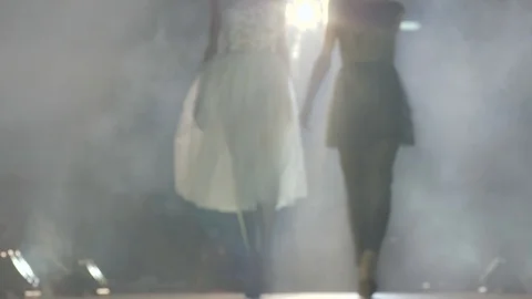 Slim silhouettes of models go along catwalk during a fashion show on background Stock Footage 85729678