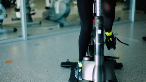 Slim sports legs pedaling on the exercise bike in the gym Stock Footage