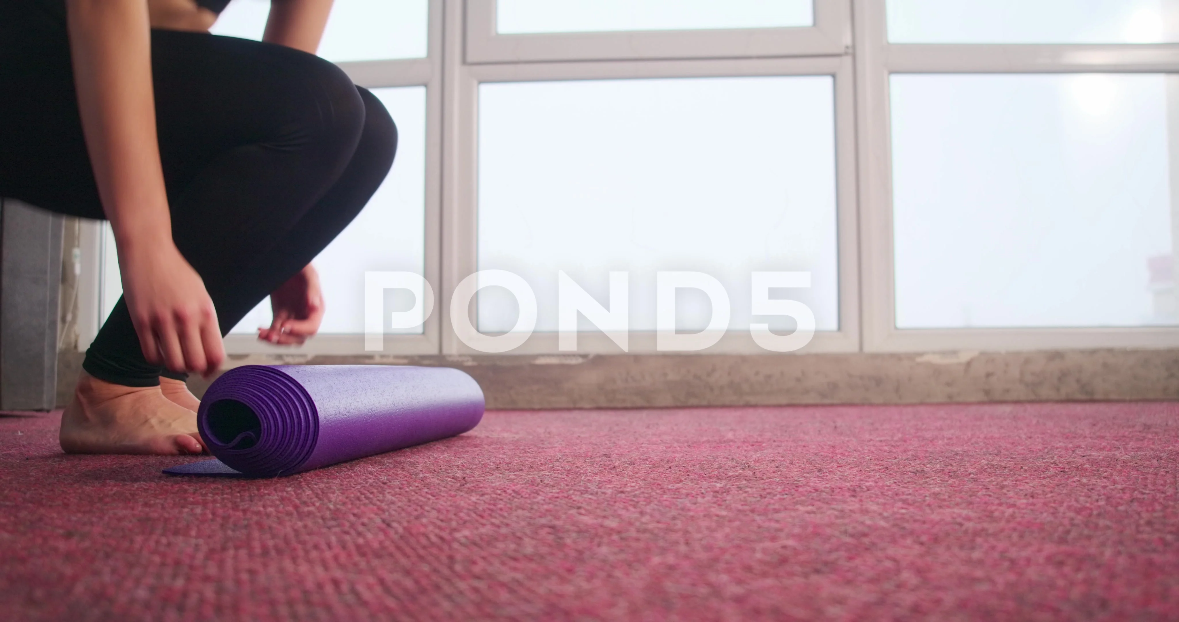 Young slim woman with blonde hair sitting on the yoga mat and
