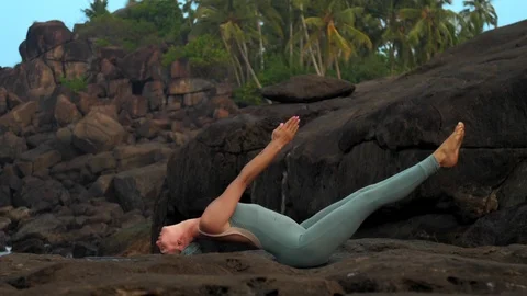 Slim woman gets out of matsyasana on flat rock slow motion Vidéo 112266393