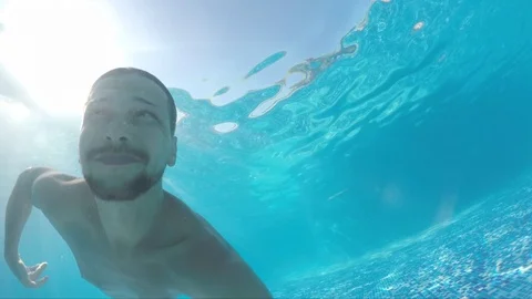 Slim young bearded guy is swimming under the blue water in swimming pool Video stock 112002121