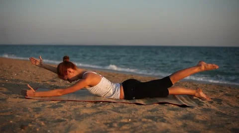 Slim young woman doing exercises for the back on the beautiful beach. Stock Footage 42701593