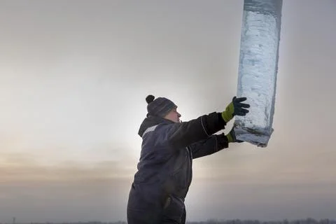 Slinger in a blue jacket unloading ice blocks 스톡 사진