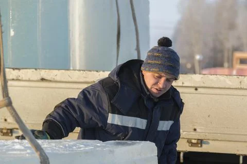 Slinger in a blue jacket unloading ice blocks 스톡 사진