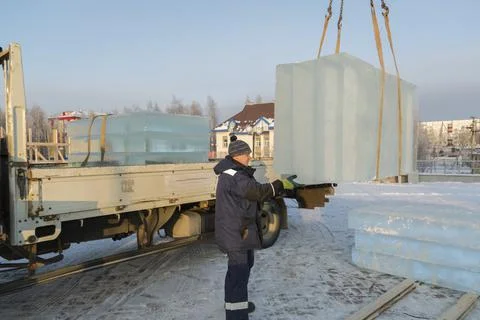 Slinger in a blue jacket unloading ice blocks 스톡 사진