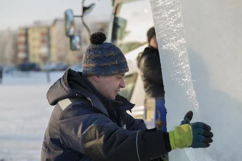 Slinger in a blue jacket unloading ice blocks 스톡 사진