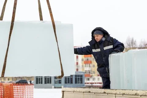 Slinger in a blue jacket unloading ice blocks 스톡 사진